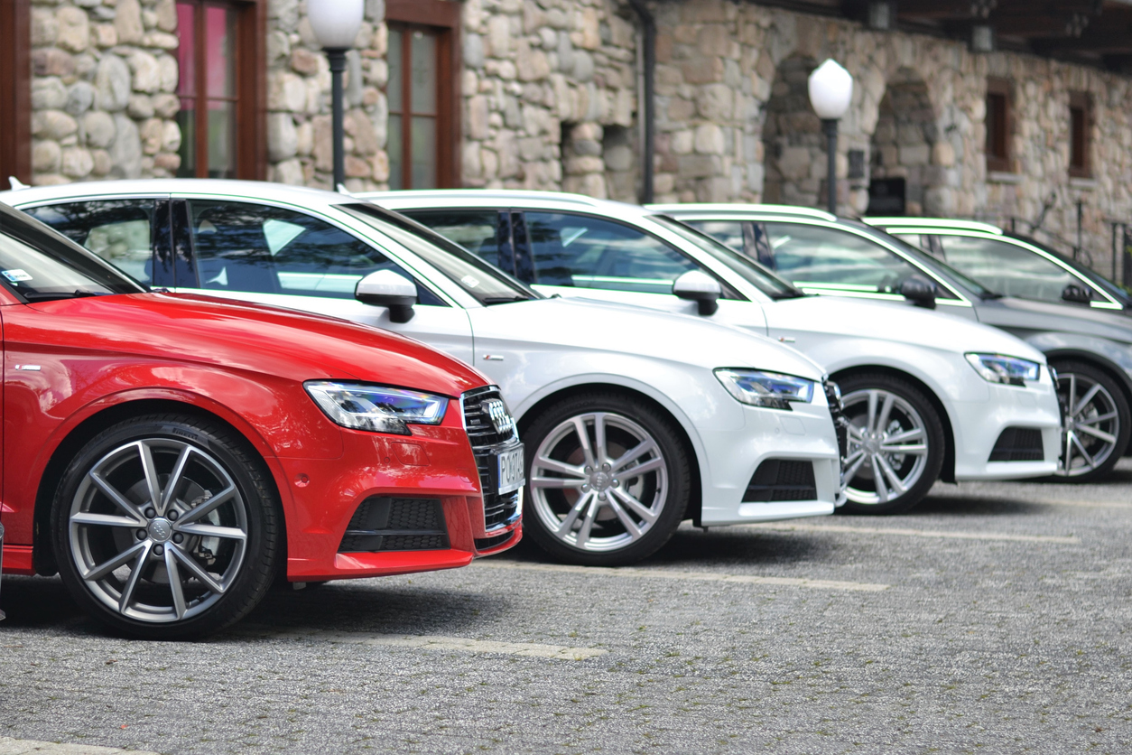 mehrere Autos nebeneinander vorne ein rotes Auto